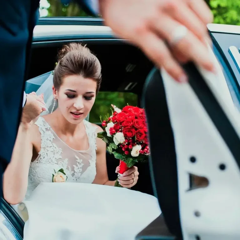Bride stepping out of a luxury wedding limo car with a bouquet, assisted by a chauffeur providing premium wedding limo service.