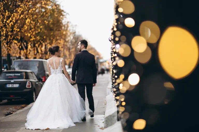 Bride and groom walking hand in hand near luxury cars on their wedding day, showcasing premium wedding limo car service.