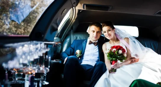 Bride and groom sitting inside a luxury wedding limo car, enjoying premium wedding transportation service.